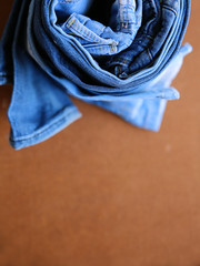 Fashionable stack of jeans, trouser, clothes on a texture backgr