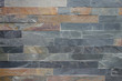 Roughly textured stone cladding tiled wall in grey and ochre colours background