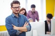 © Wavebreak Media - Businessman with arms crossed standing against coworkers
