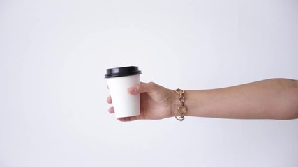 Wall Mural - Woman hand with bracelet moves smoothly white paper cup from right side to center and takes away