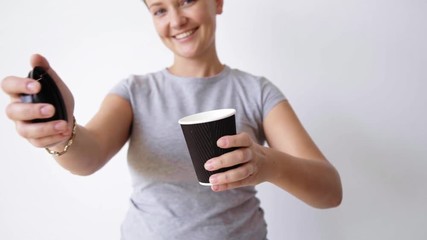 Wall Mural - Smiling young woman opens and close cap on black paper cup