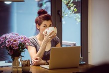 Hipster Drinking A Cup Of Coffee While Using A Laptop
