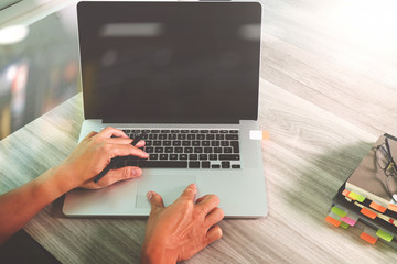 designer hand working with laptop computer on wooden desk as res