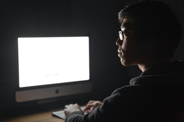 Canvas Print - Focused man using blank screen computer in dark room