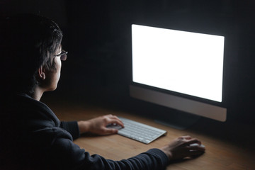 Wall Mural - Man sitting at table and using computer in dark room