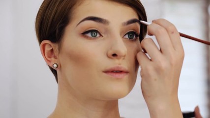 Wall Mural - Close up of female arm of makeup artist drawing a shape of eyebrows using cosmetic brush