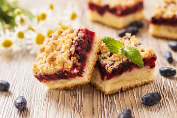 Wall Mural - Honeysuckle Crumb Cake  sliced into pieces on a light background with berries of honeysuckle and flowers 