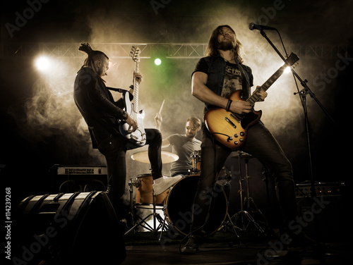 Zdjęcie XXL Zespół rockowy występuje na scenie. Gitarzysta, gitara basowa i perkusja. Gitarzysta gra solo.