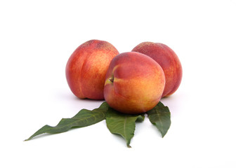 Fresh nectarines and green leaves isolated on the whtie background