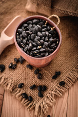 vigna mungo or black beans in wooden cup with wooden scoop on s