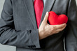 © twinsterphoto - Businessman showing compassion holding red heart onto his chest