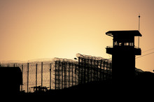 Silhouette Of Barbed Wires And Watchtower Of Prison In Neapolis, Crete, At Sunset 