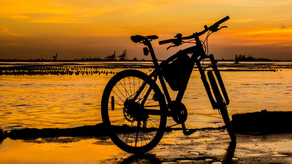 Silhouette of bicycle at jetty with sunset sky and sea backgroun