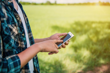 closeup of a young man using a smartphone in a natural landscape, with a meadow in the background