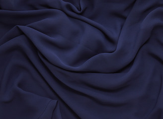 Fabric textures - a full frame close up of dark navy blue silk / satin material, for use as a page background