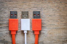 Orange And White USB Cable Plug On Wooden Background.