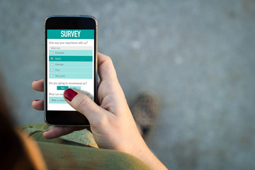 Wall Mural - woman walking and filling online survey form with a smartphone