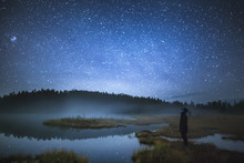 Side View Of A Man Standing In Forest Against Starry Sky At Night