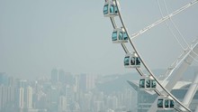 Video 1080p - Enormous, White Ferris Wheel Turns Slowly Against The Dramatic Backdrop Of A Major Metropolitan City In Asia, With Towers And Skyscrapers In The Hazy Distance.