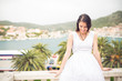 © eldarnurkovic - Young beautiful woman in white dress standing on villa terrace enjoying the summer holiday. Finding your inner peace. Girl enjoying her earned vacation. Smiling to problems. Paradise on earth.