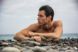 © theartofphoto - Young shirtless athletic man laying down on pebbles