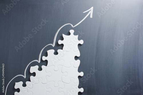 Fotomural Steps shaped jigsaw puzzle and up arrow on blackboard
