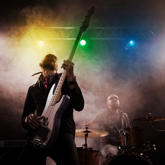 Poster - Rock band performs on stage. Bassist in the foreground.