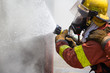 fireman in fire fighting suit spraying water to fire surround wi