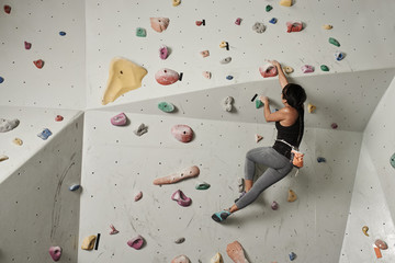 Wall Mural - Girl climbing indoors, view from the back