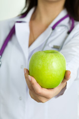 Close up view of medical doctor hand offering green apple