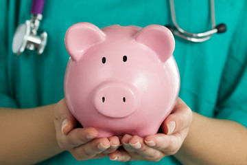 Female medicine doctor holding piggy bank