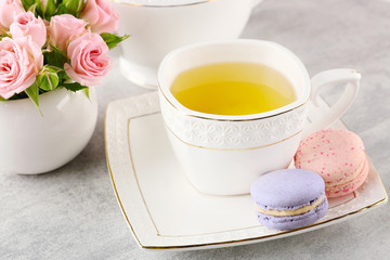 Wall Mural - Cup of tea with macaroons and roses on wooden table