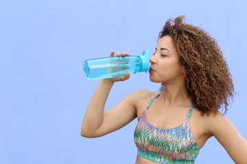 Young woman drinking water after jogging with copy space