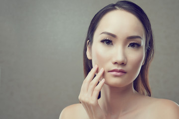 Portrait of pretty Chinese woman touching her face