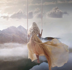 Attractive lady sitting on the swing above the calm lake