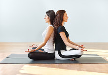 Two Young Women Meditating In Lotus Pose