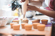 © morrowlight - Woman making creamy top of cupcakes closeup. Selective focus.