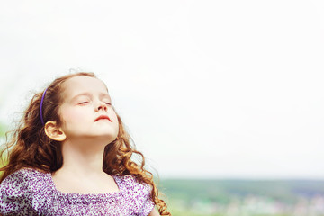 Wall Mural - Little girl closed her eyes and breathes the fresh air in the pa