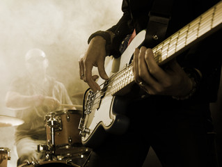 Sticker - Rock band performs on stage. Bassist in the foreground. Close-up.