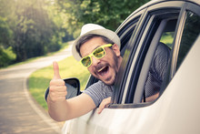 Young Man Wearing Hat And Sunglasses Showing Thumbs Up From Driver’s Seat Through Opened Window. Vacation And Travel Concepts. 