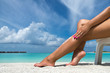 © gawriloff - Woman applying sunblock cream on leg on beautiful tropical beach