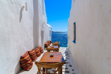 Wall Mural - Benches with pillows in a typical Greek bar in Mykonos town with sea view, Cyclades islands, Greece