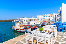 Taverna Tables And Typical Greek Fishing Boats In Naoussa Port, Paros Island, Cyclades, Greece