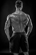 © nazarovsergey - Muscular bodybuilder guy doing posing over black background