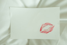 Sexy Girl Red Lips Kiss On Blank White Note Paper On White Bed In The Morning Light. 
Romantic Message From Couple. 