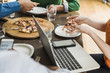 © Westend61 - Colleagues at table with cell phone and laptop having a pizza