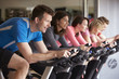 Side view of a spinning class on exercise bikes at a gym