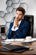 © Cookie Studio - Young successful businessman sitting at workplace, office background.