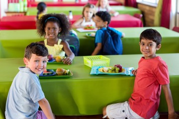 Wall Mural - Cute schoolchildren having meal