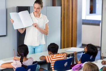 Wall Mural - Teacher showing book to schoolchildren